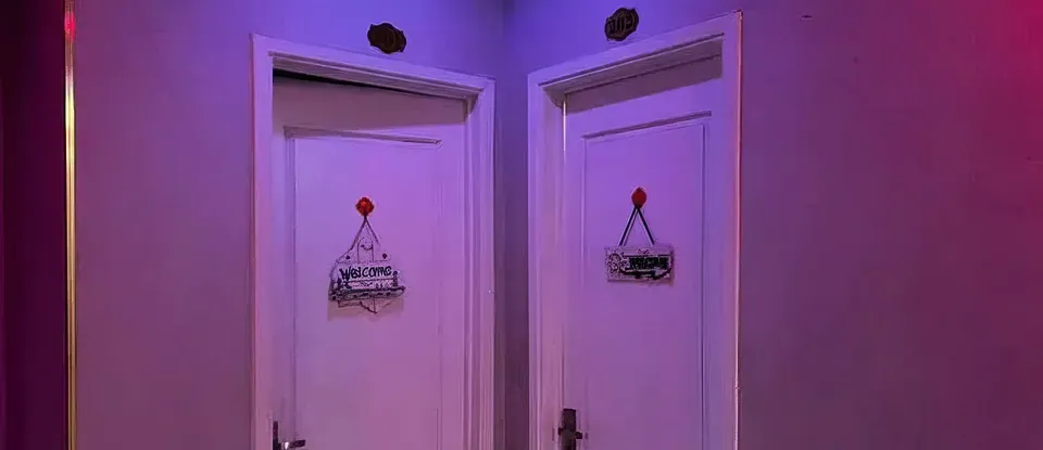 보라색 조명 아래 나란히 있는 마사지실 문