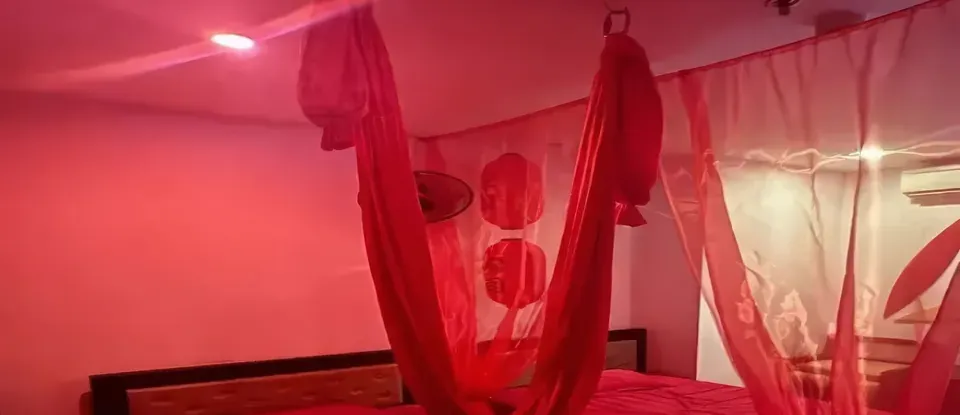 붉은 조명 아래 천이 매달린 침실