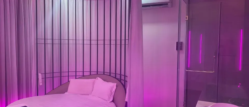 보라색 조명 아래 둥근 침대와 샤워실